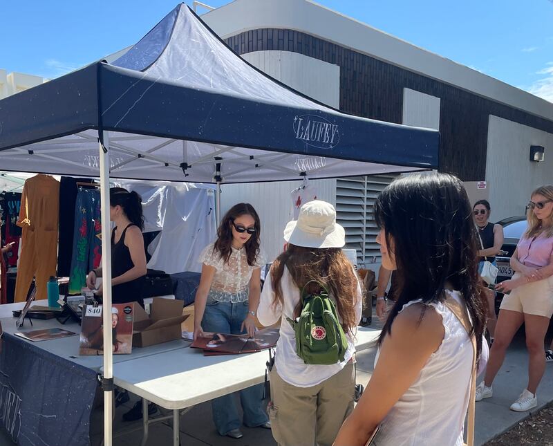 Photo of a person at a booth signing vinyl records for people in line