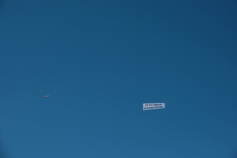 A banner reading “GOP 2024: A Race For The Extreme MAGA Base” flies over the Republican debate.