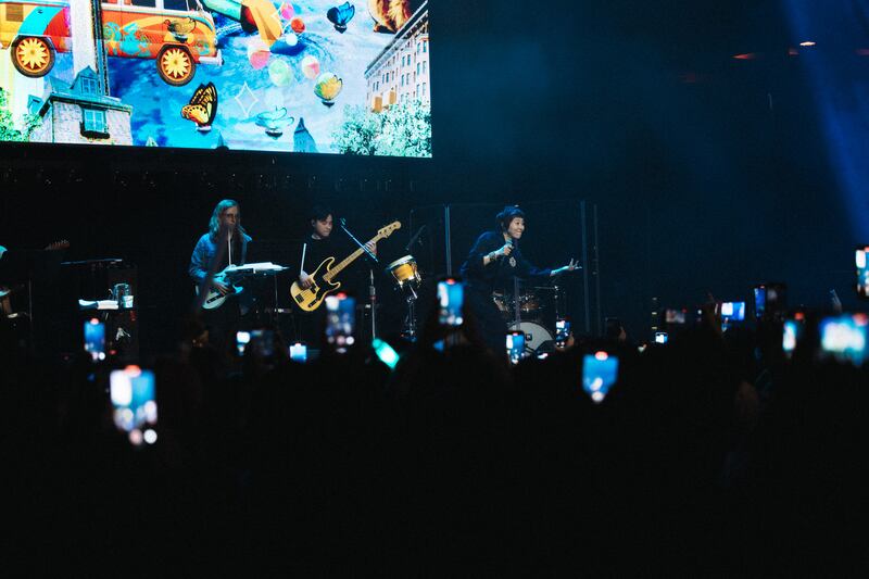 Photo of a crowd of phones in front of a stage with a singer and a guitarist