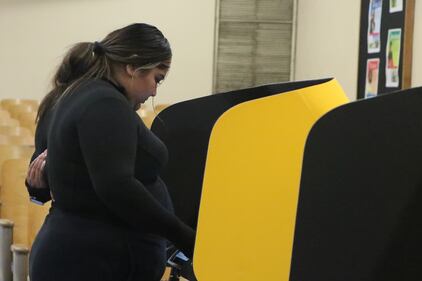 A first time voter at the polls casting their ballot at a voting booth.