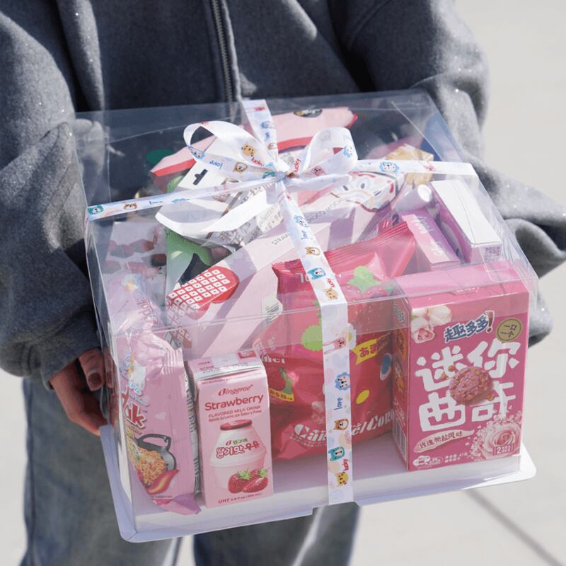 Photo of a person holding a clear box with pink snacks and a bow