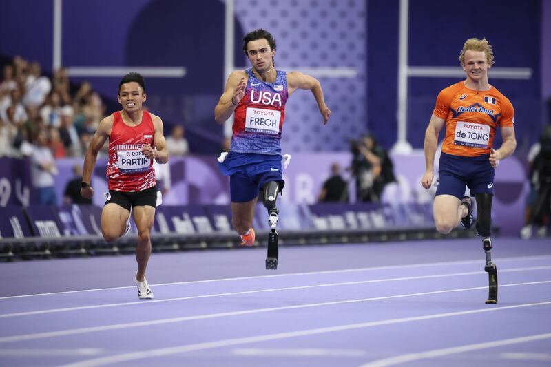 Photo of three men running on a track.