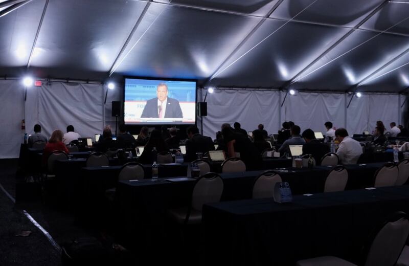 Reporters watch the debate while working on their stories.