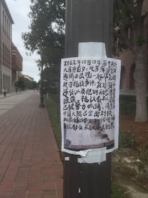 A poster with Chinese writing posted on a lamppost.