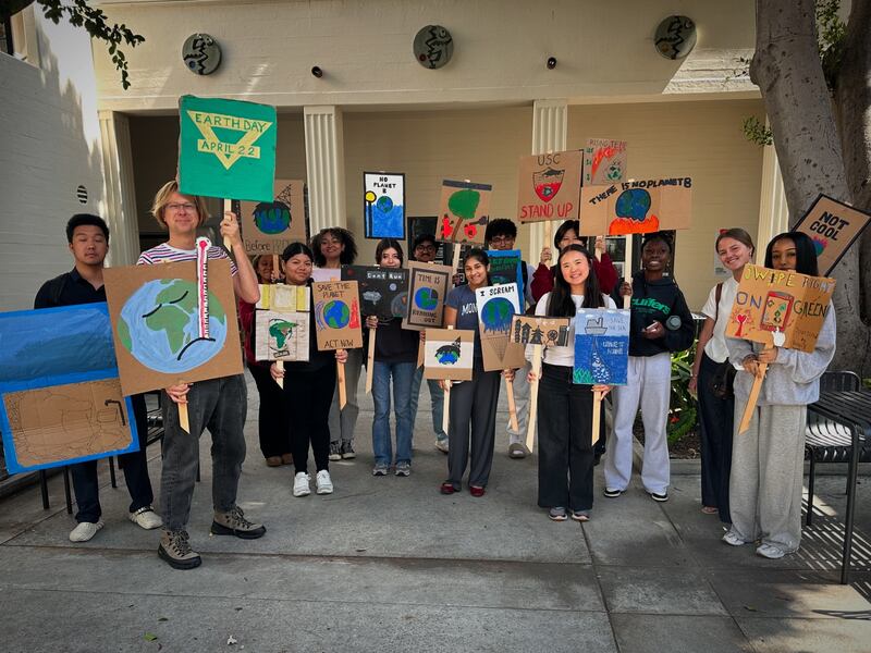 Kelley holds two posters with his freshman seminar class students for Earth Day 2025.