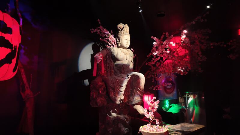Photo of a statue in front of neon red lanterns
