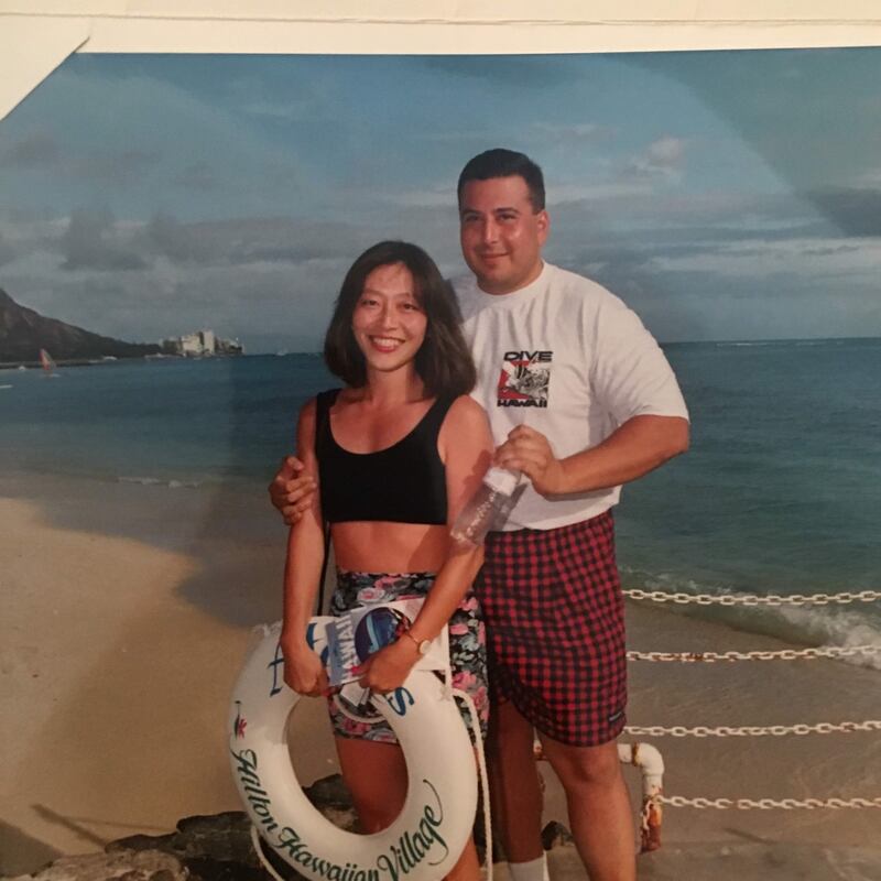 Two people, a man and a woman, posing next to a beach.