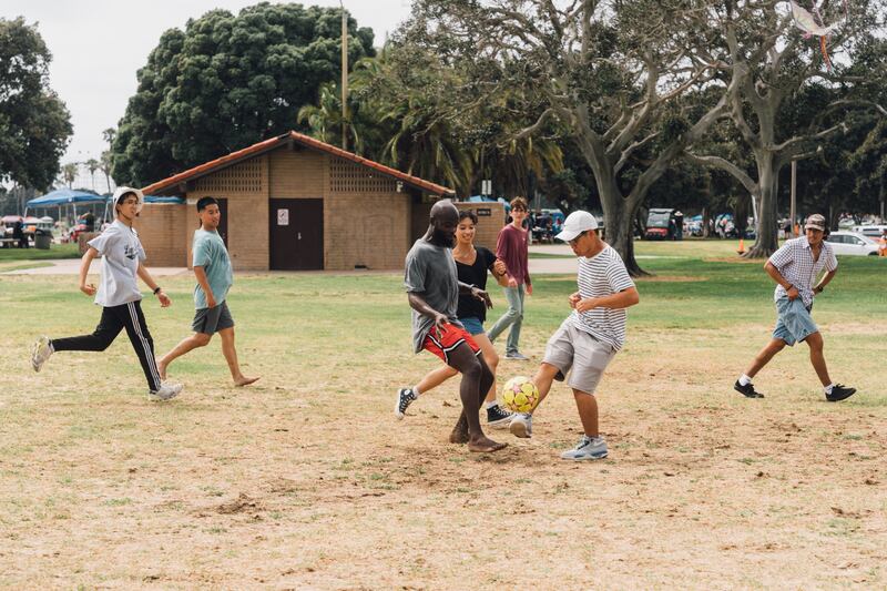 People play soccer in a grass field.