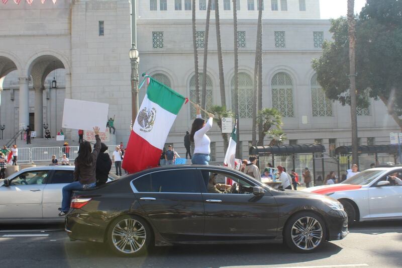 Photo of protestors waving a Mexican flag from their car.