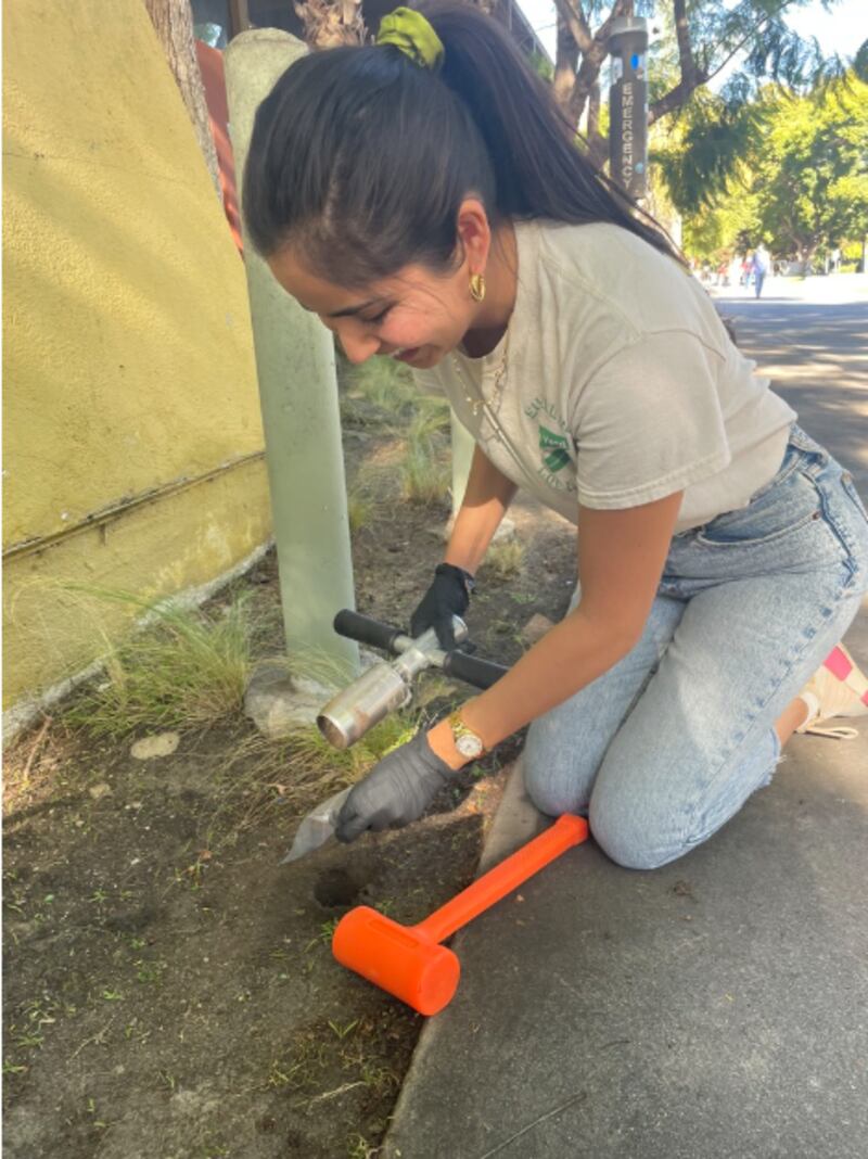 Venezia Ramirez demonstrates how a soil sample is collected.