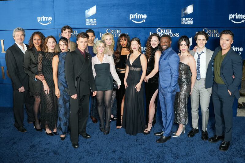The cast and crew smile on the blue carpet.