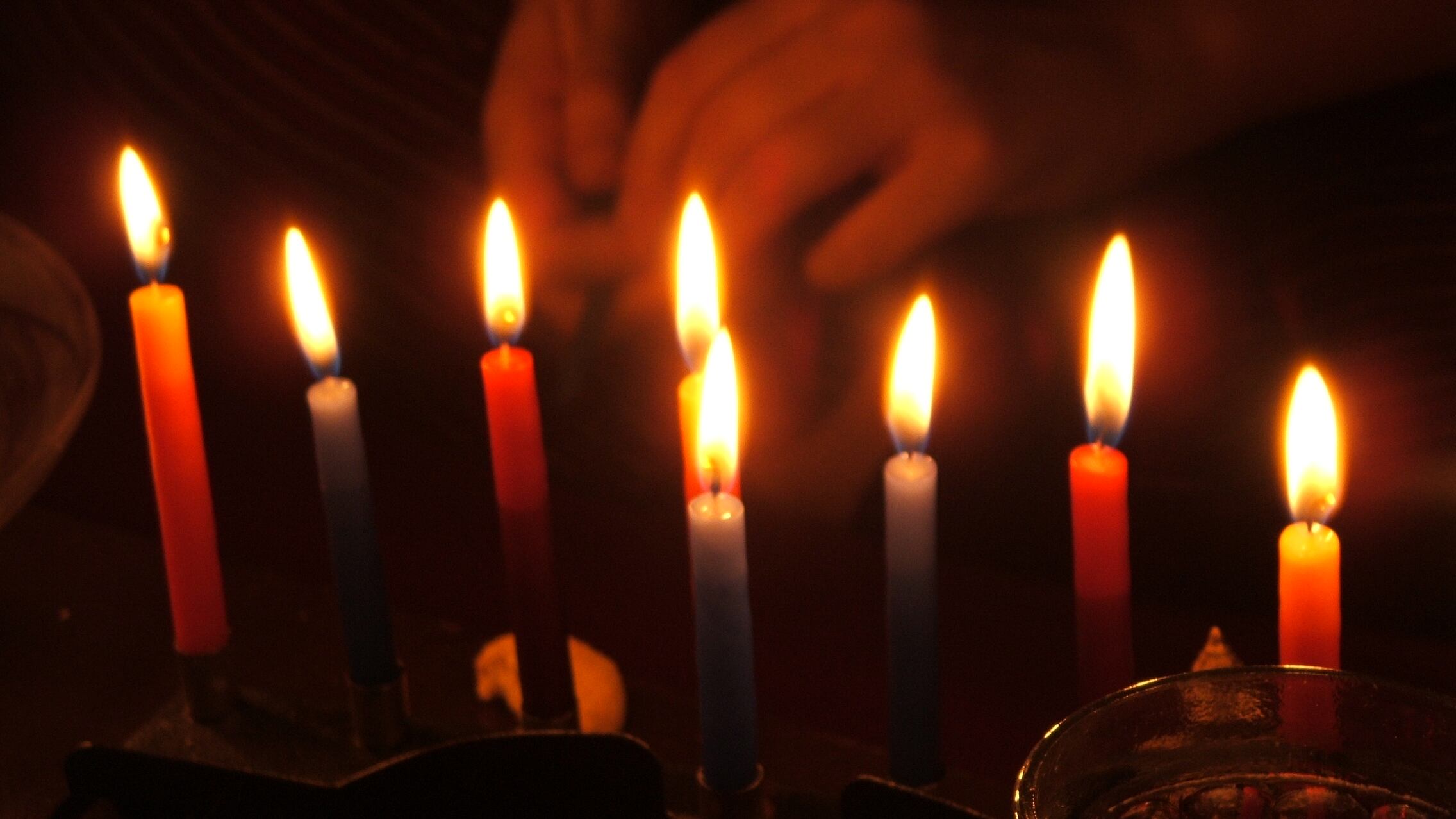 A photo of a Menorah being lit with candles.