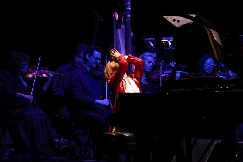 Photo of a man at a piano leaning back with his hands together