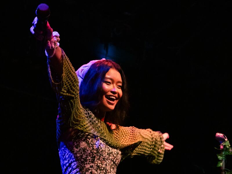Photo of a woman holding her arms out with a microphone