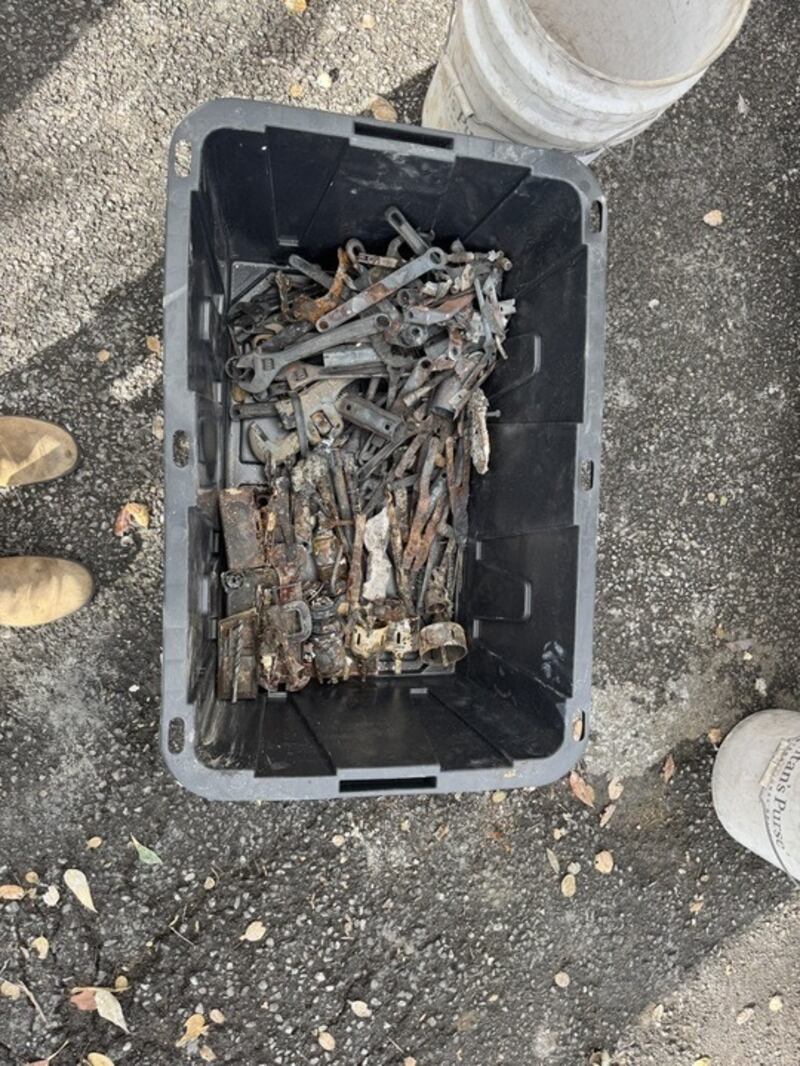 A plastic bin with rusty, fire-burnt tools.